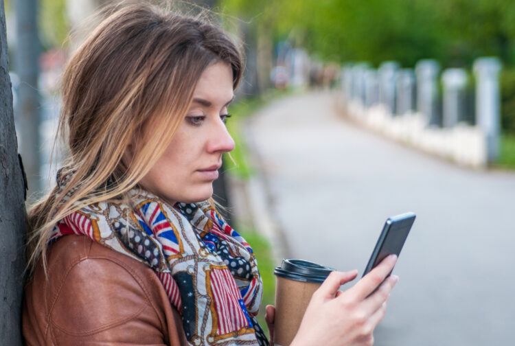 stressed beautiful woman walking on the street looking at her cellphone