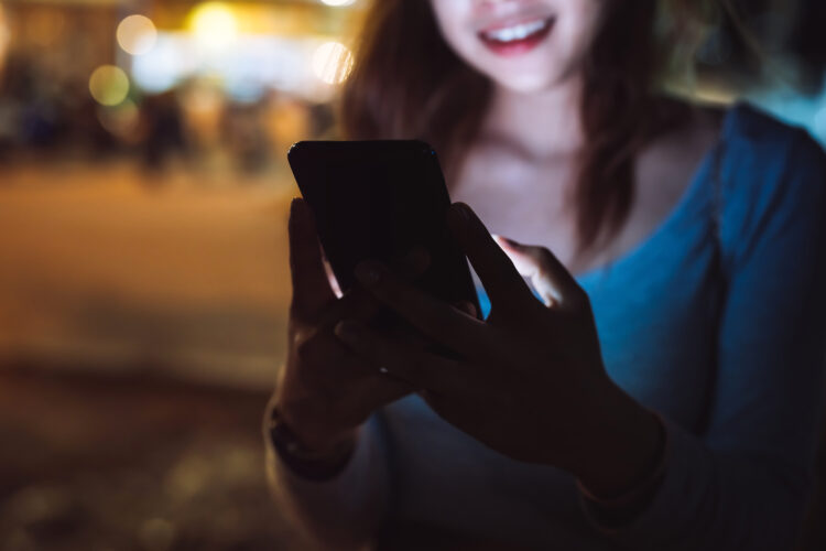 Beautiful woman looking smartphone at night on the street