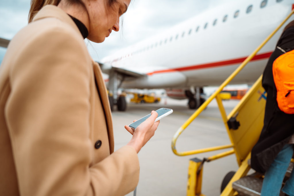 Young woman texting while boarding the aircraft.