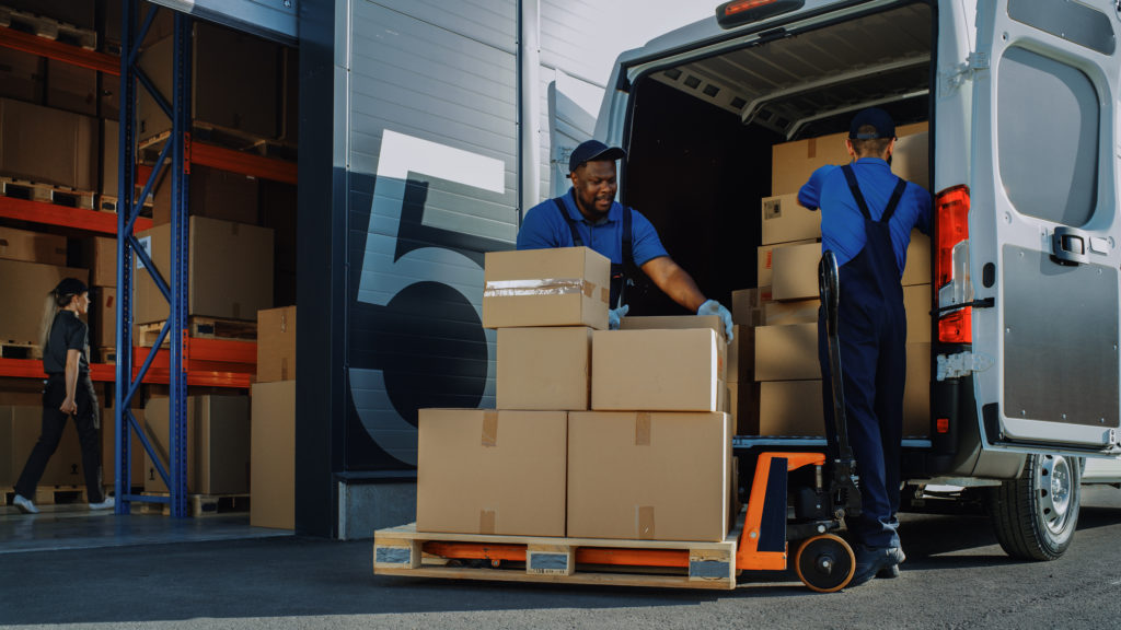 Delivery van loading packages outside of logistics warehouse which is the in between phase when a package left an amazon facility but not out for delivery.