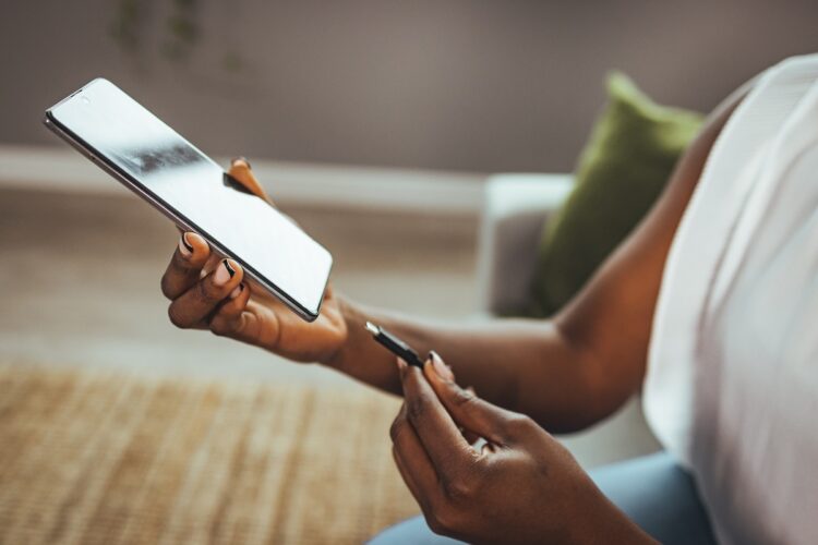 Female hand plugging charger to smart phone at home. 