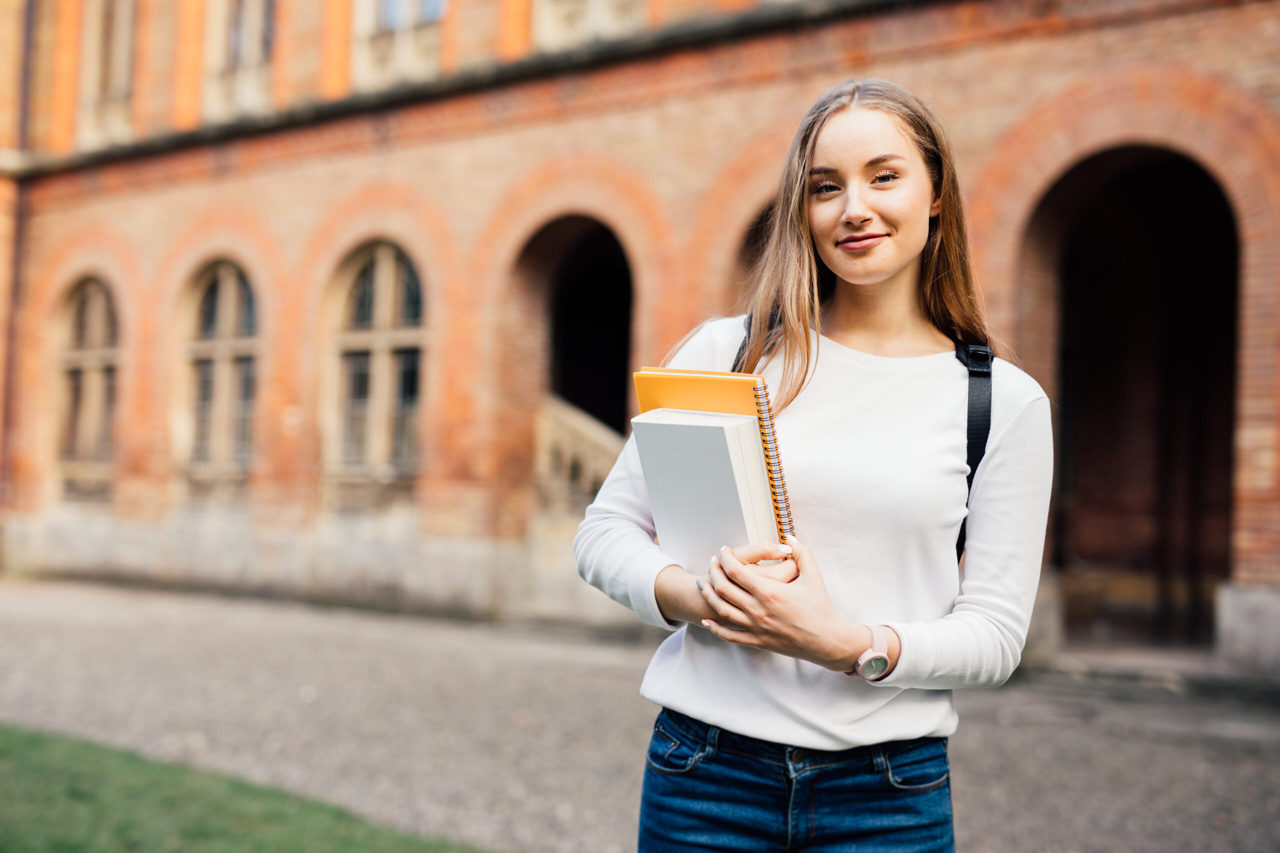 happy female university student with books standing on campus