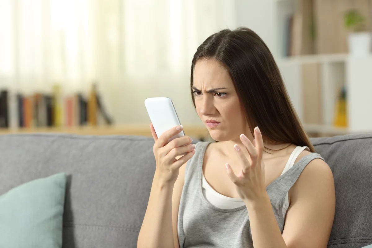 Woman annoyed looking at smart phone at home.