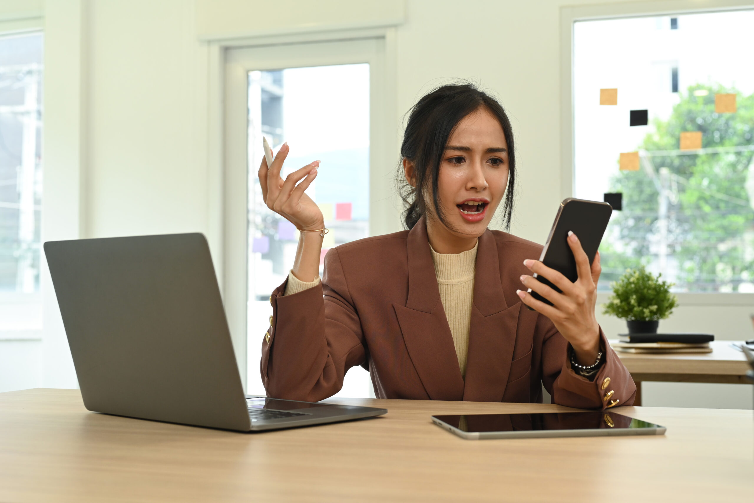 irritated woman staring at mobile phone screen, sitting at the desk