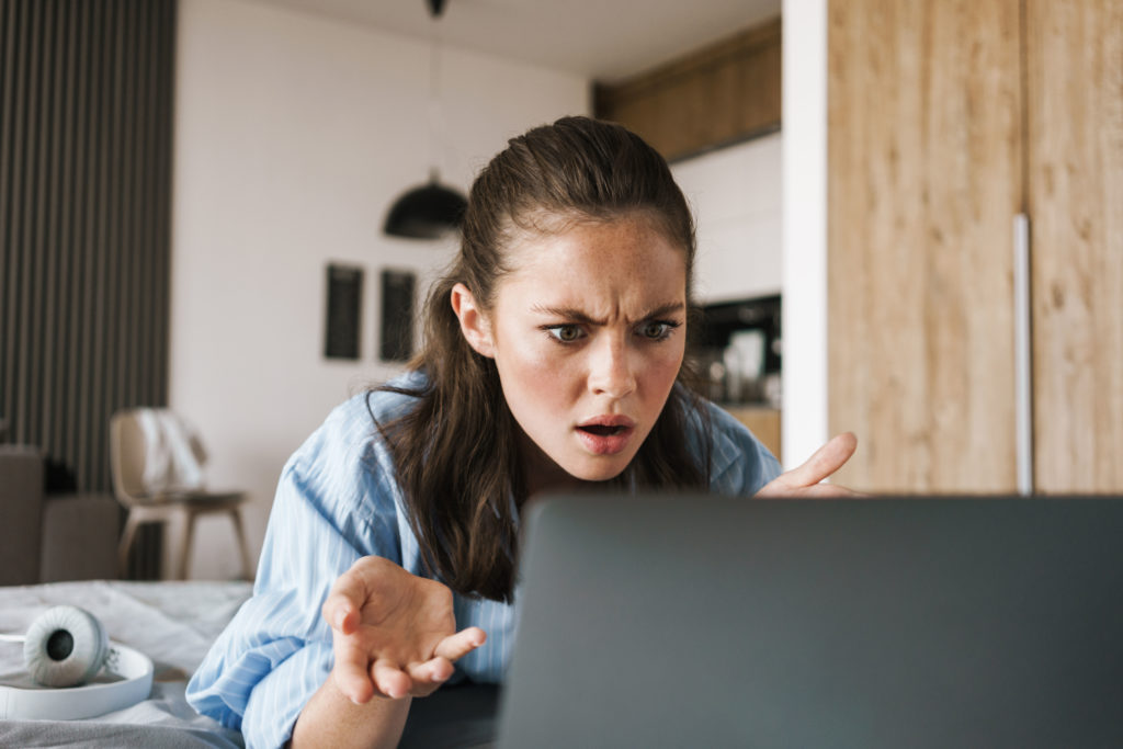 Displeased angry girl using her laptop.