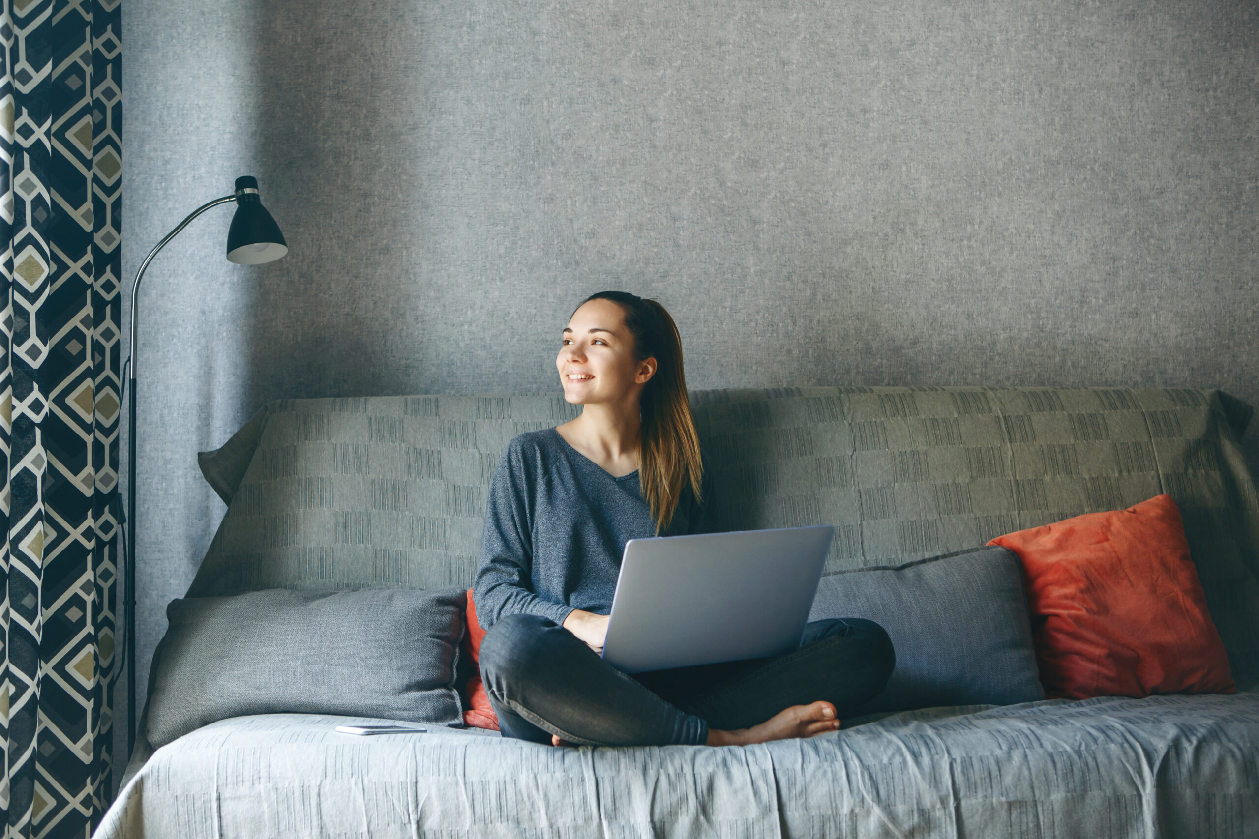 happy woman with laptop sitting on couch