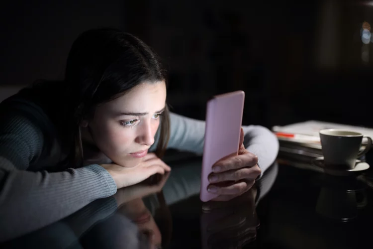Sad female checking phone content in the night at home