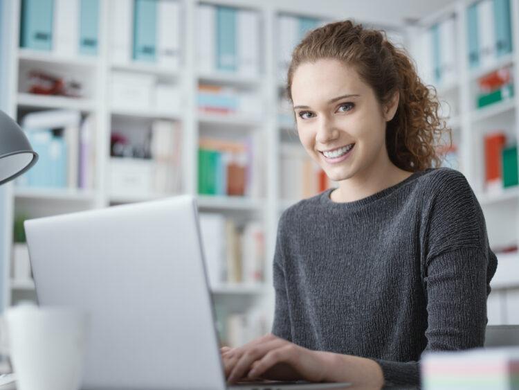 Young woman smiling while using her laptop
