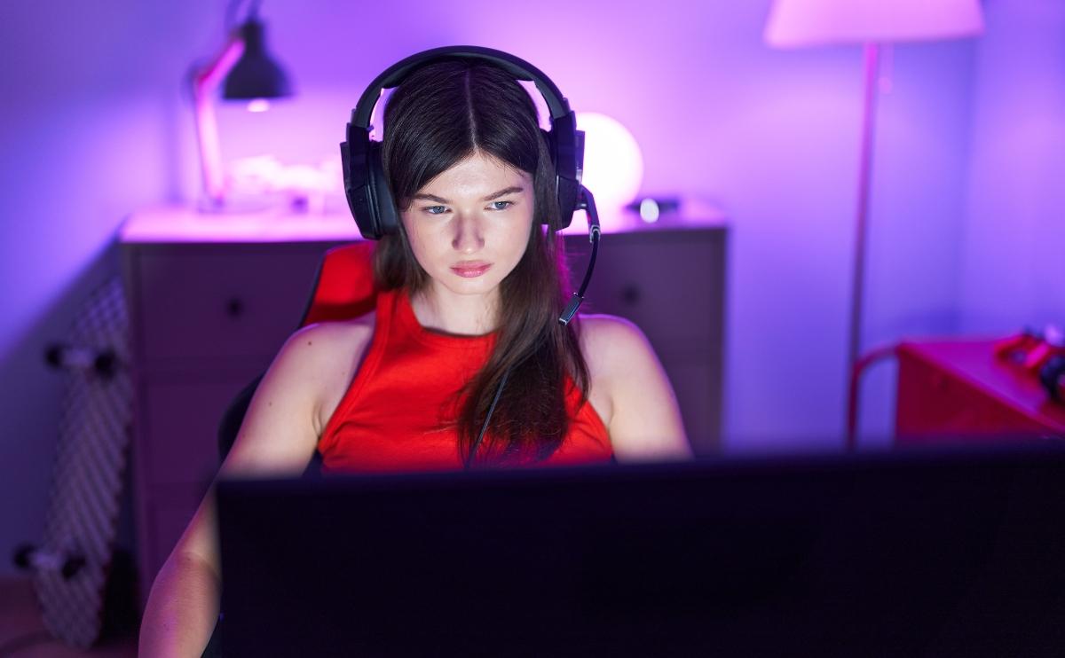 Young Caucasian female streamer with serious expression looking at the computer