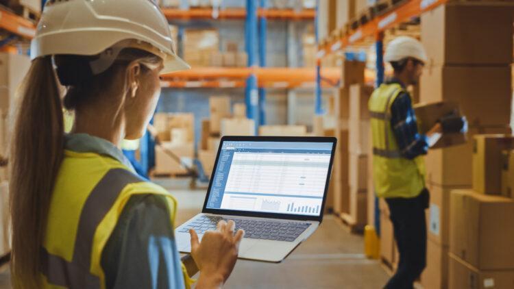 female warehouse worker holding laptop checking inventory
