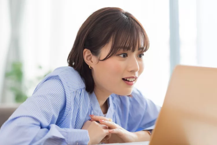 Pretty Asian young woman looking at laptop smiling