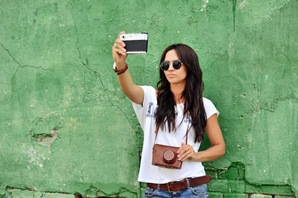 Beautiful girl taking pictures of herself on vintage camera