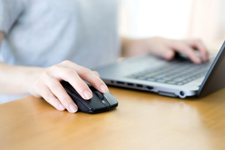 female hands clicking computer mouse typing on laptop keyboard