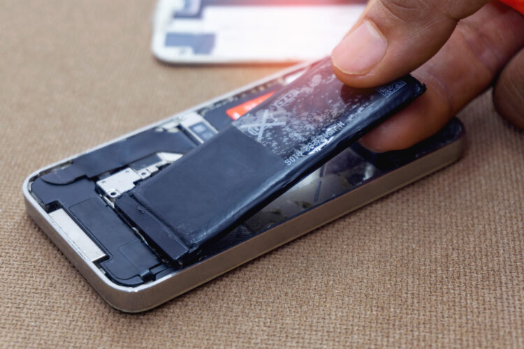 Male hand removes battery and repair motherboard for smartphone.