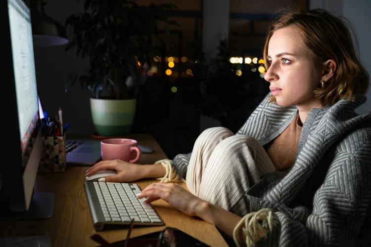 Young woman working on desktop pc late at night at home.