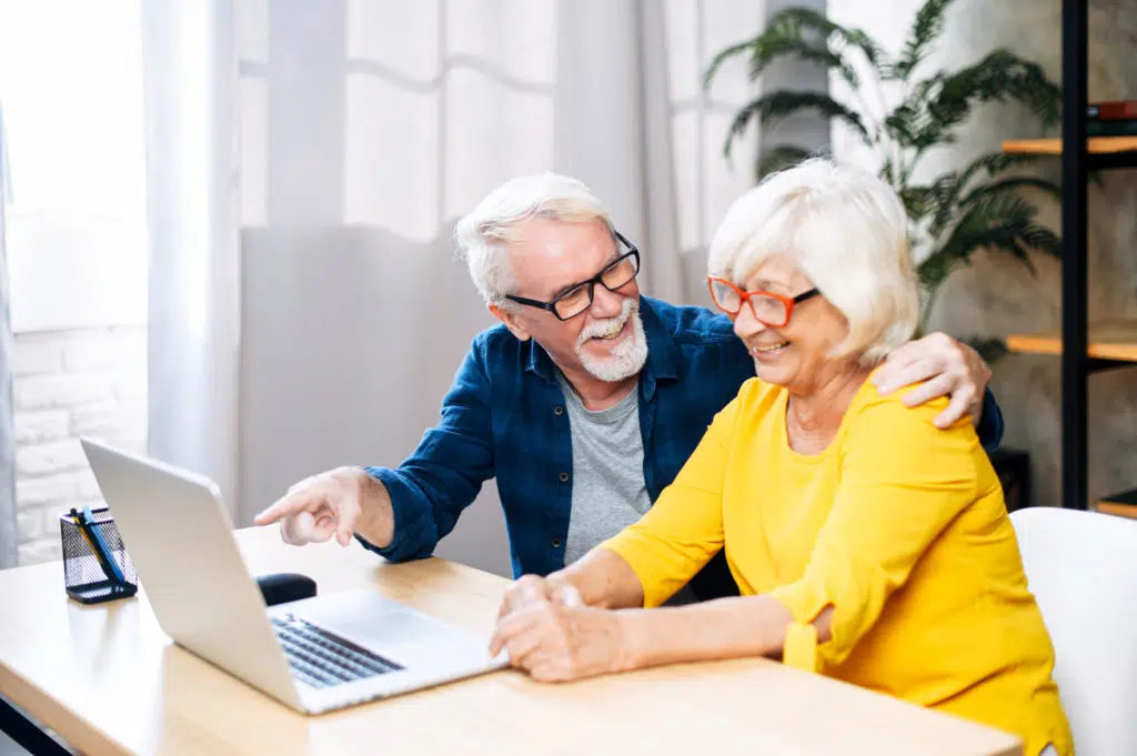 Cheerful elderly couple enjoys using the laptop.