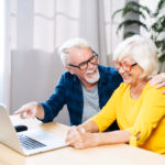 Cheerful elderly couple enjoys using the laptop.