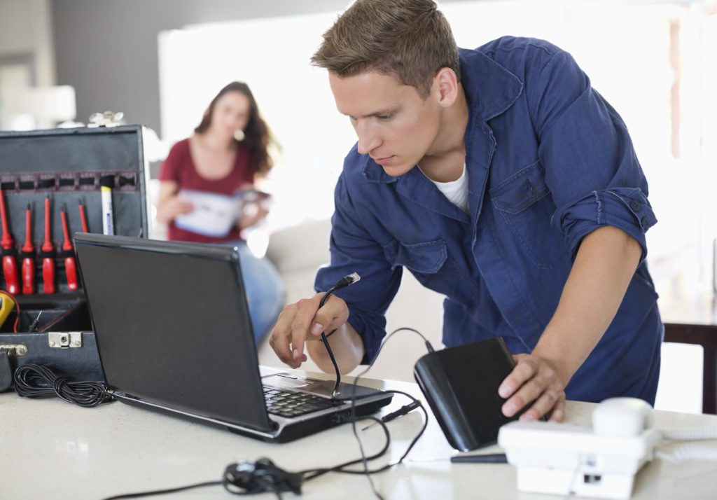 Electrician fixing and testing laptop indoors.