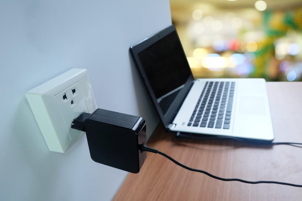Laptop charging on a wall outlet.
