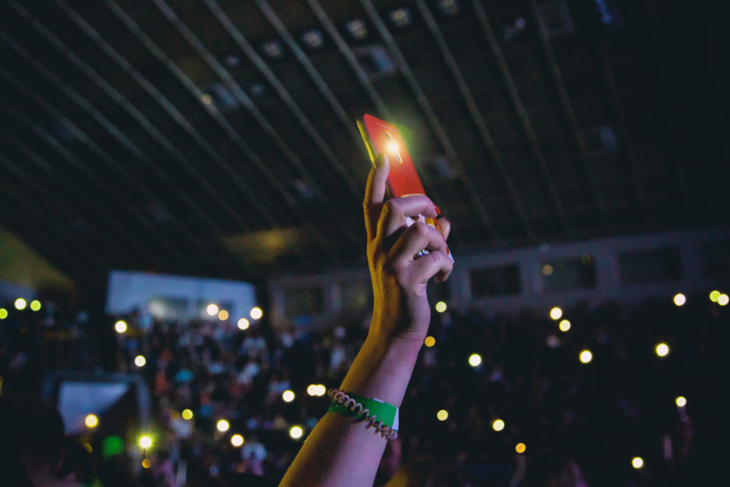 Smartphone in a female hand at a concert.