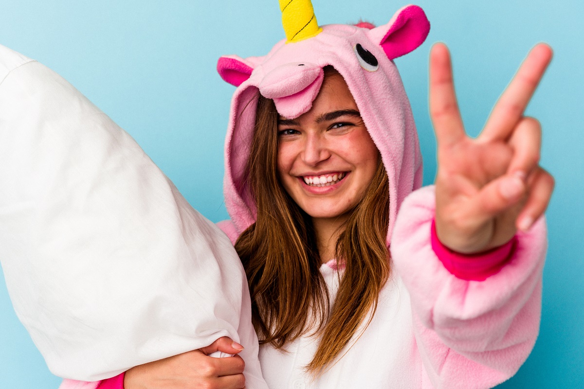 Young cute woman wearing a unicorn pajama holding a pillow