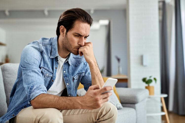 Distraught man using cell phone at home.