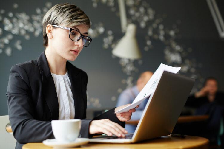 Confident young woman with short stylish haircut working on her laptop in a coffeeshop