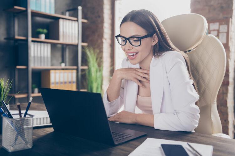 Pretty and chic lady at her workstation sending emails on her laptop