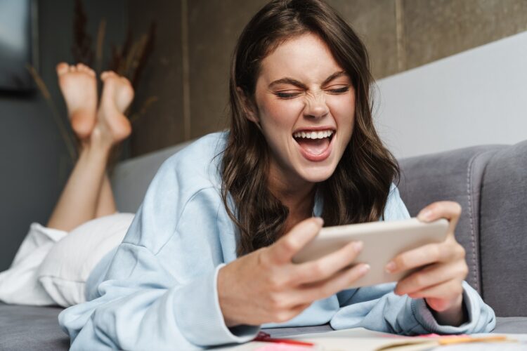 cheerful woman using her phone while lying on the couch