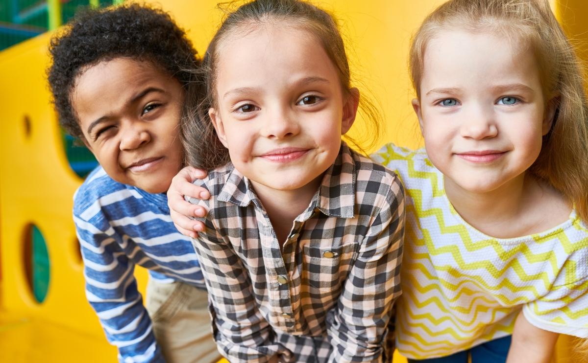 three smiling kids in the playground