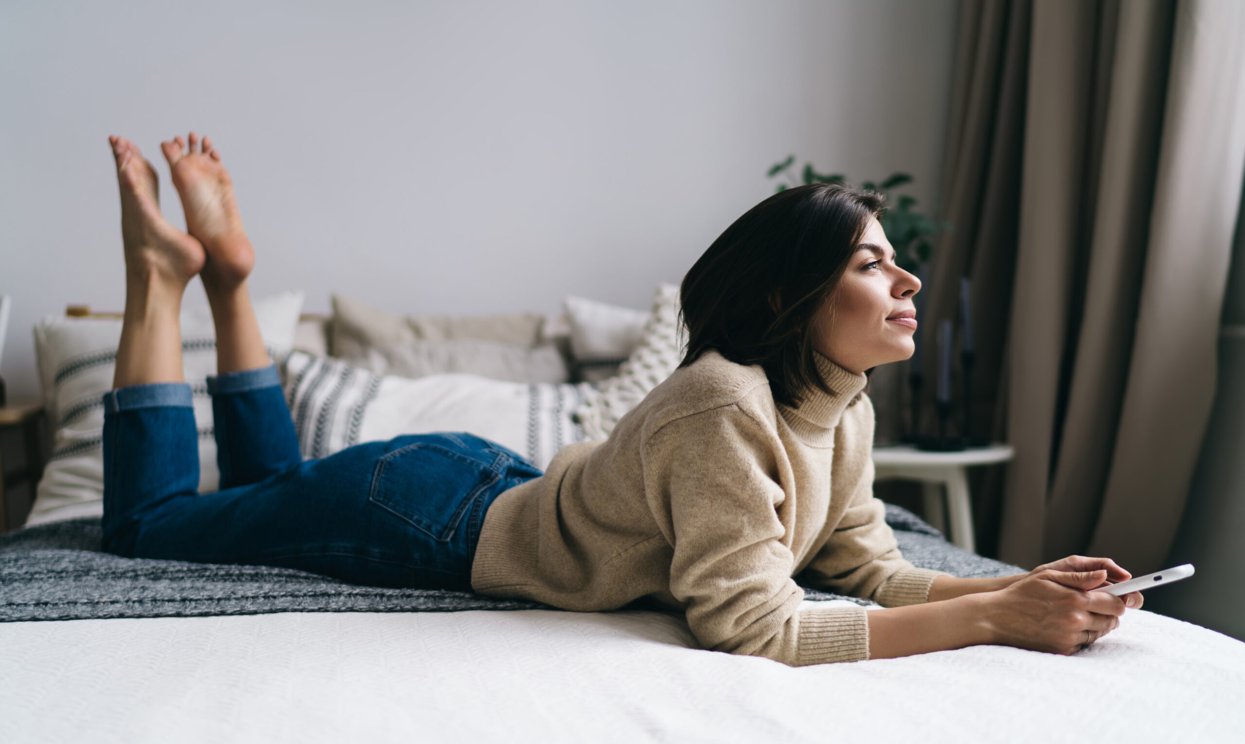 Relaxed young ethnic woman browsing mobile phone on bed