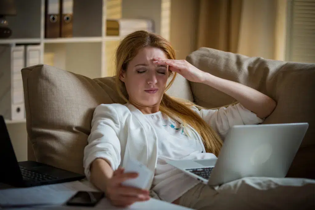 Exhausted business woman working on the couch while having a headache.