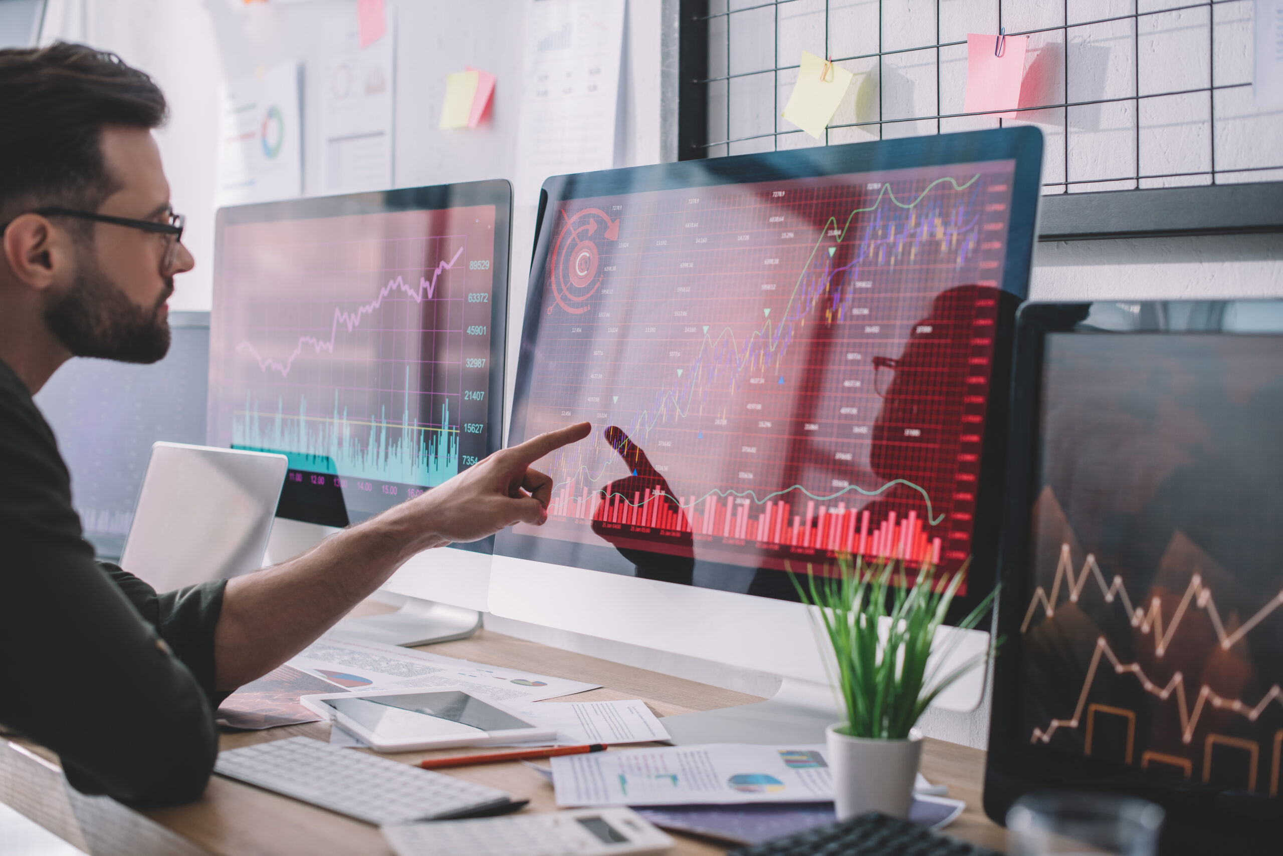 Side view of data analyst pointing with finger at charts on comp