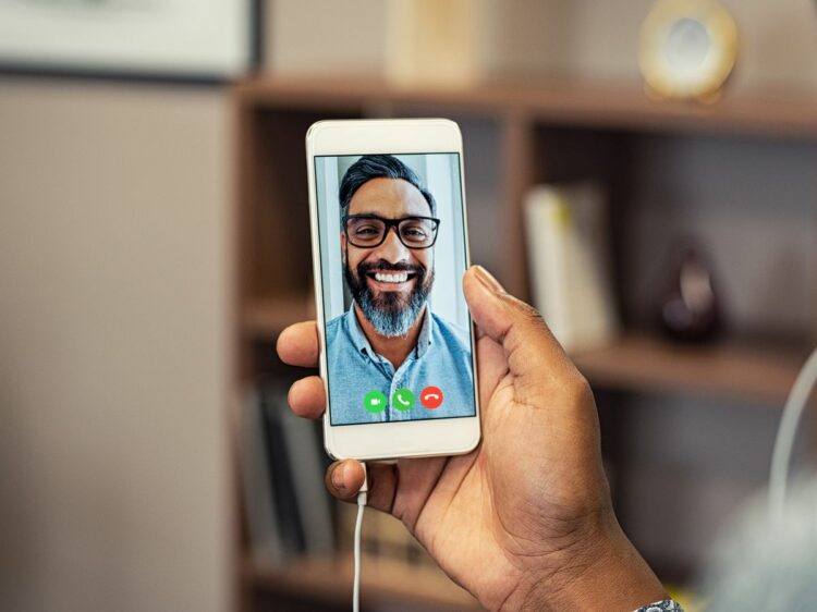 Person holding phone with lagging Facetime because of poor connection.