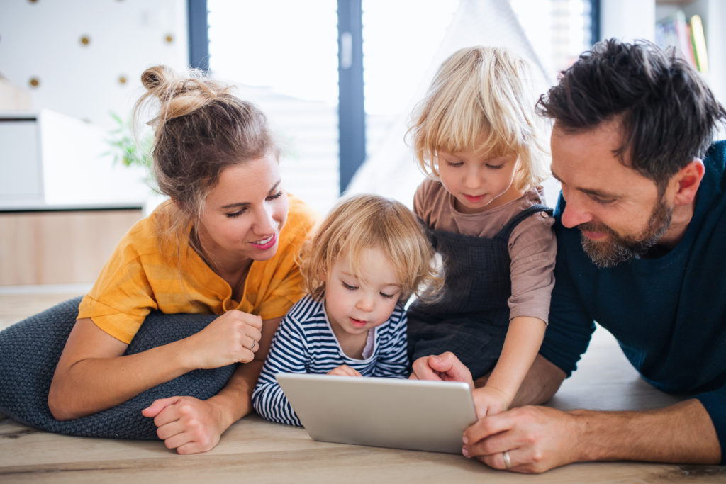 Young family with two small children using tablet indoors.