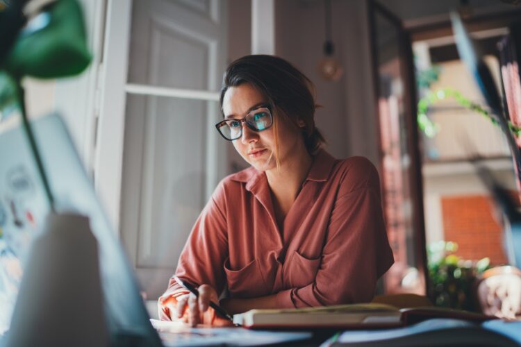 Pretty young woman wearing eyeglasses working intently on computer.