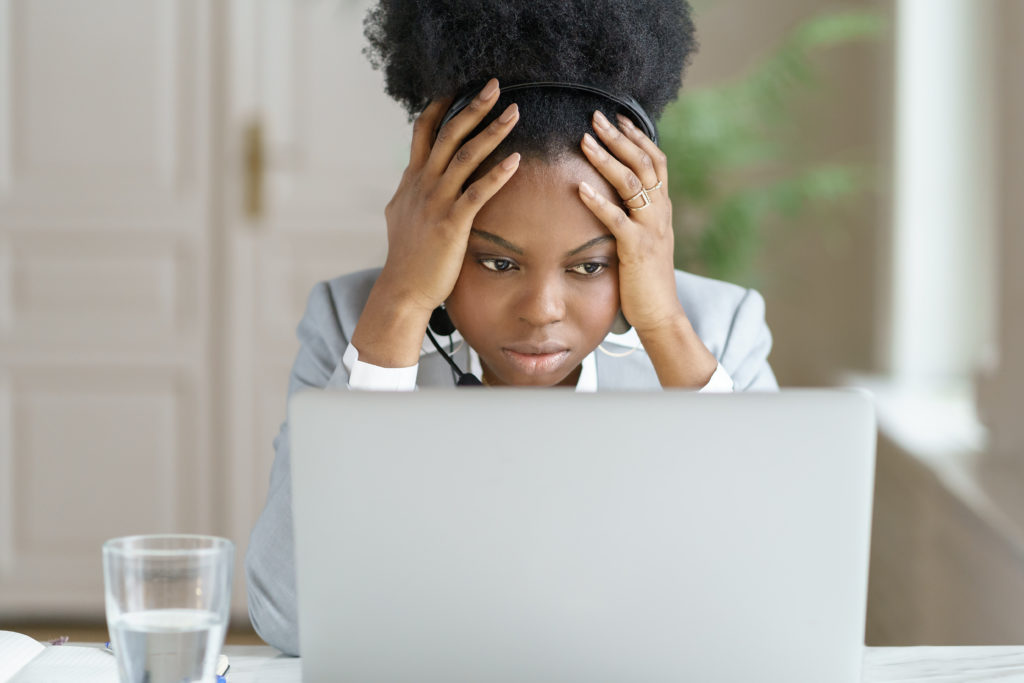 Tired and annoyed woman wear headphones looking at her laptop