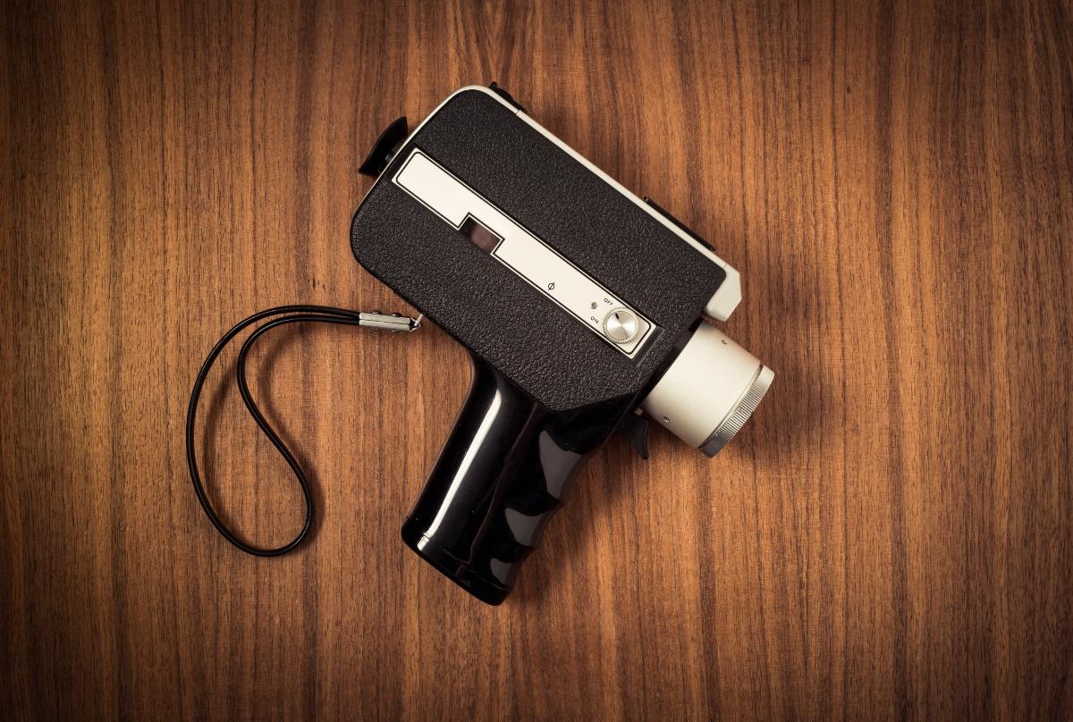 Old retro 8 mm movie camera lying on wooden table