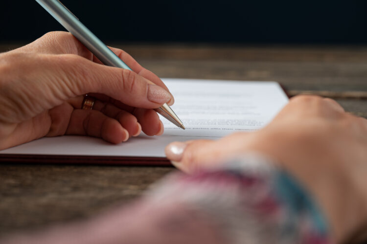 polished female hand signing a document