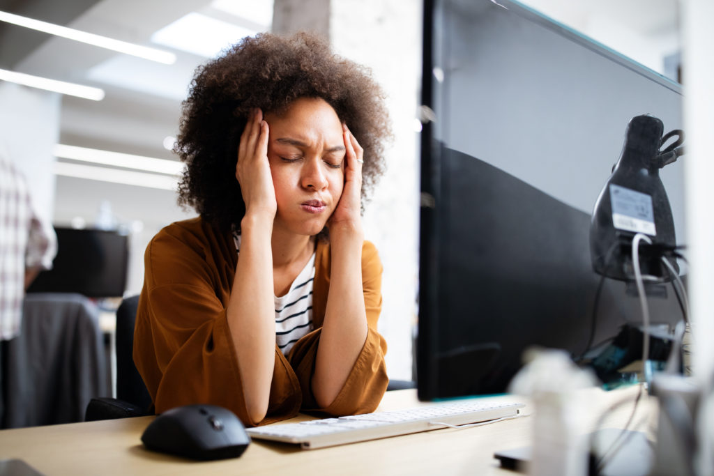 Frustrated woman in front of a computer inside the office.