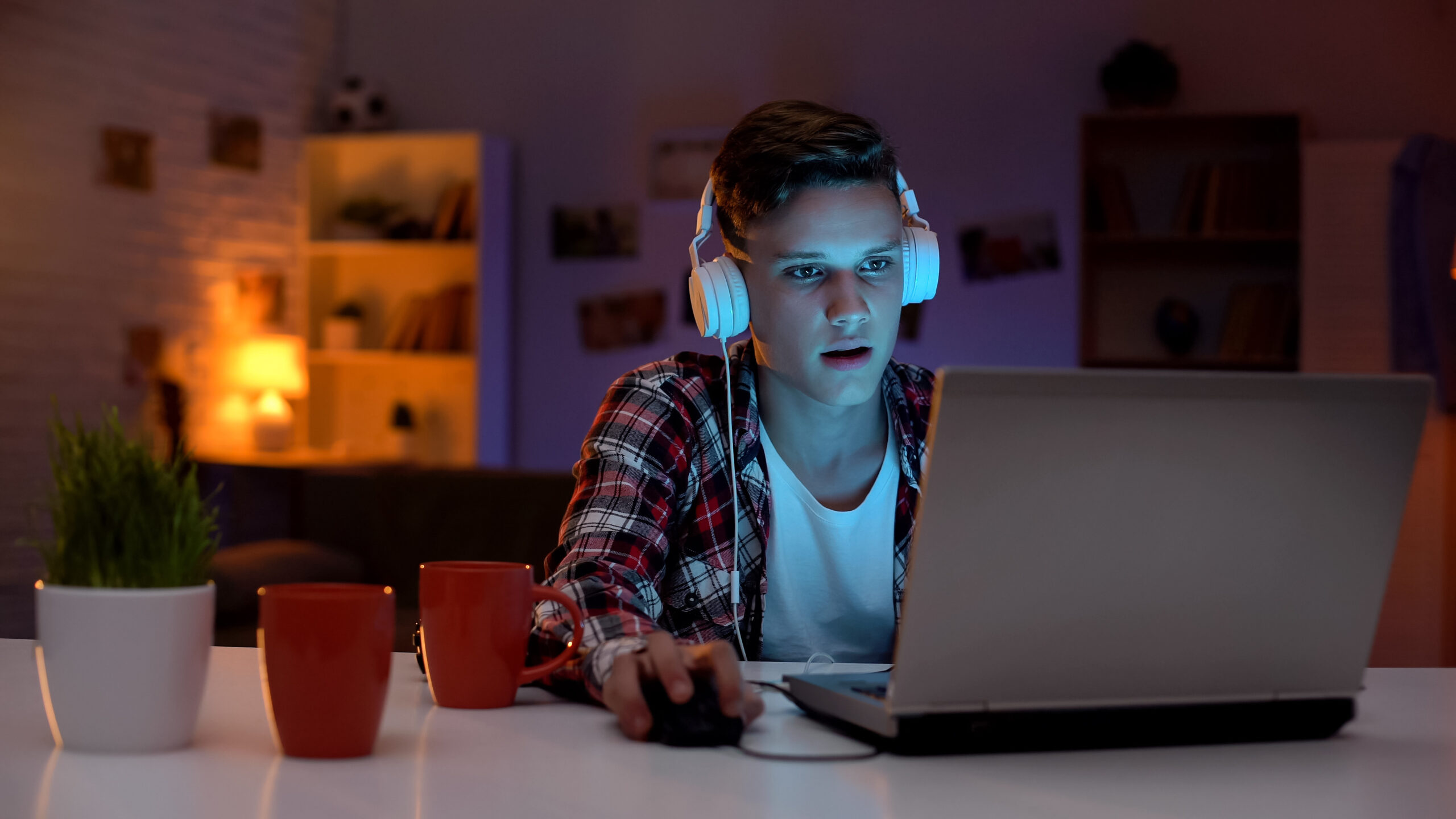 addicted male teen playing computer games on laptop