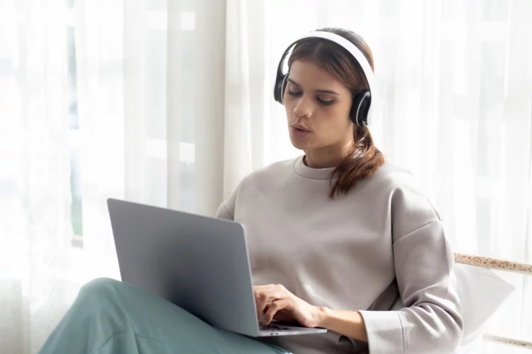 Happy young woman wearing headphones while using laptop