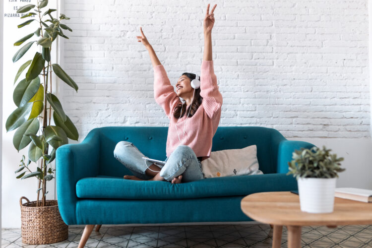 Motivated young woman listening to music with digital tablet on sofa at home.