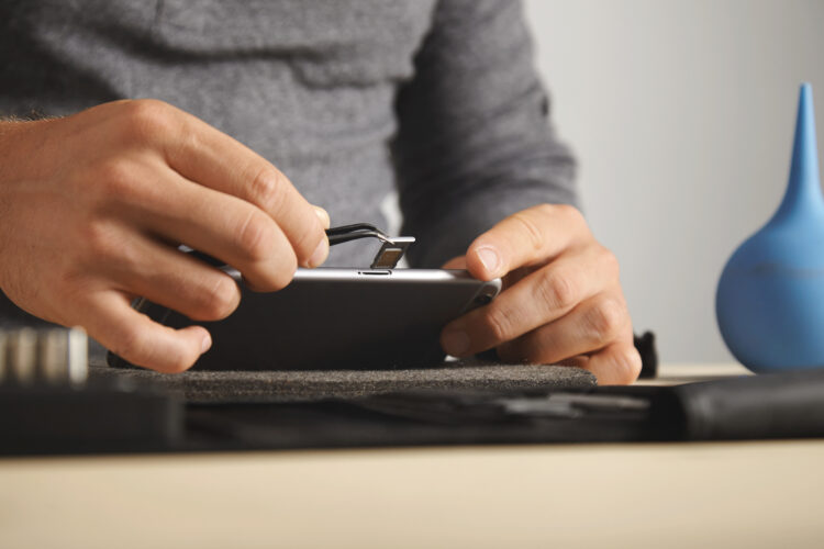 repairman pulling out a SIM card from a phone