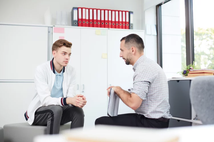 a teacher talking to an anxious male student
