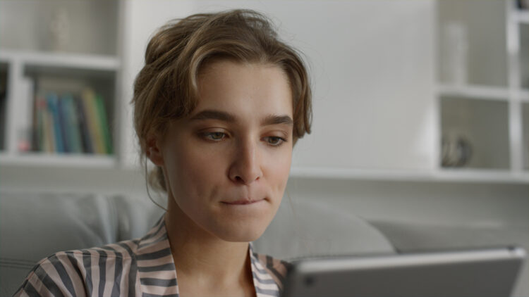 Serious woman browsing internet online biting lips in living room