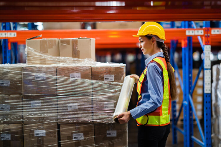 A female worker wrapping a packages in a large warehouse before customs clearance completed for Amazon packages.