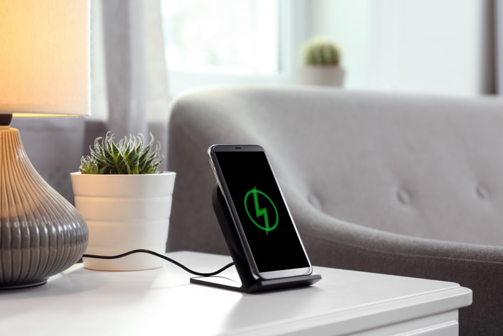 Smartphone charging on a wireless pad in a room.