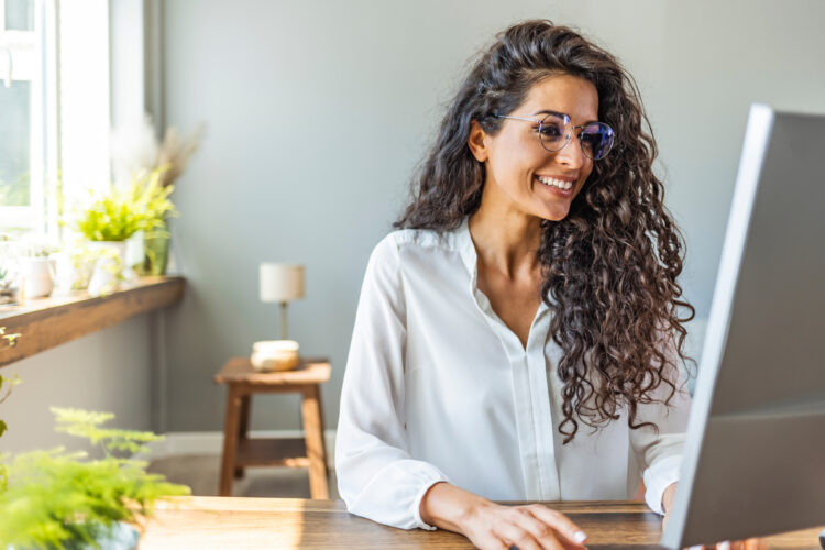 Cheerful professional woman working at her computer at home office.