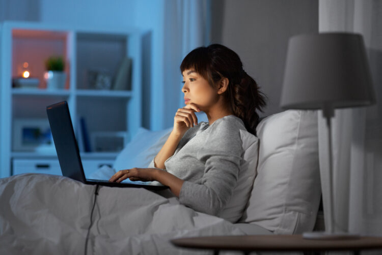 woman with laptop in bed at home at night